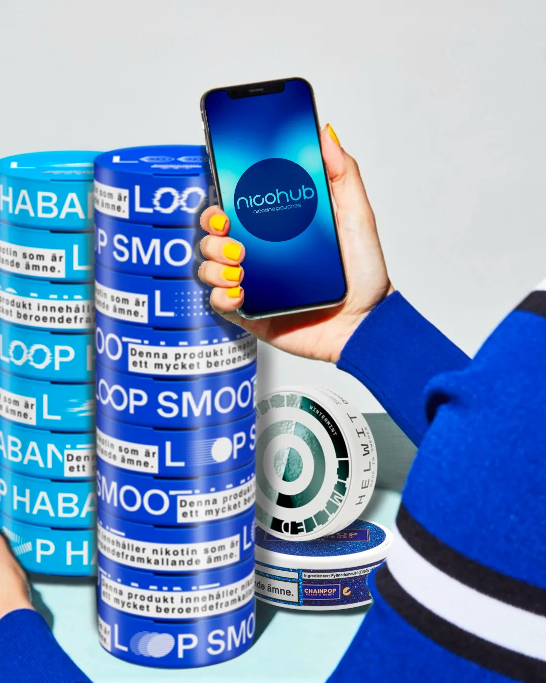 Person holding a phone with a nicohub app, surrounded by nicotine pouches cans 